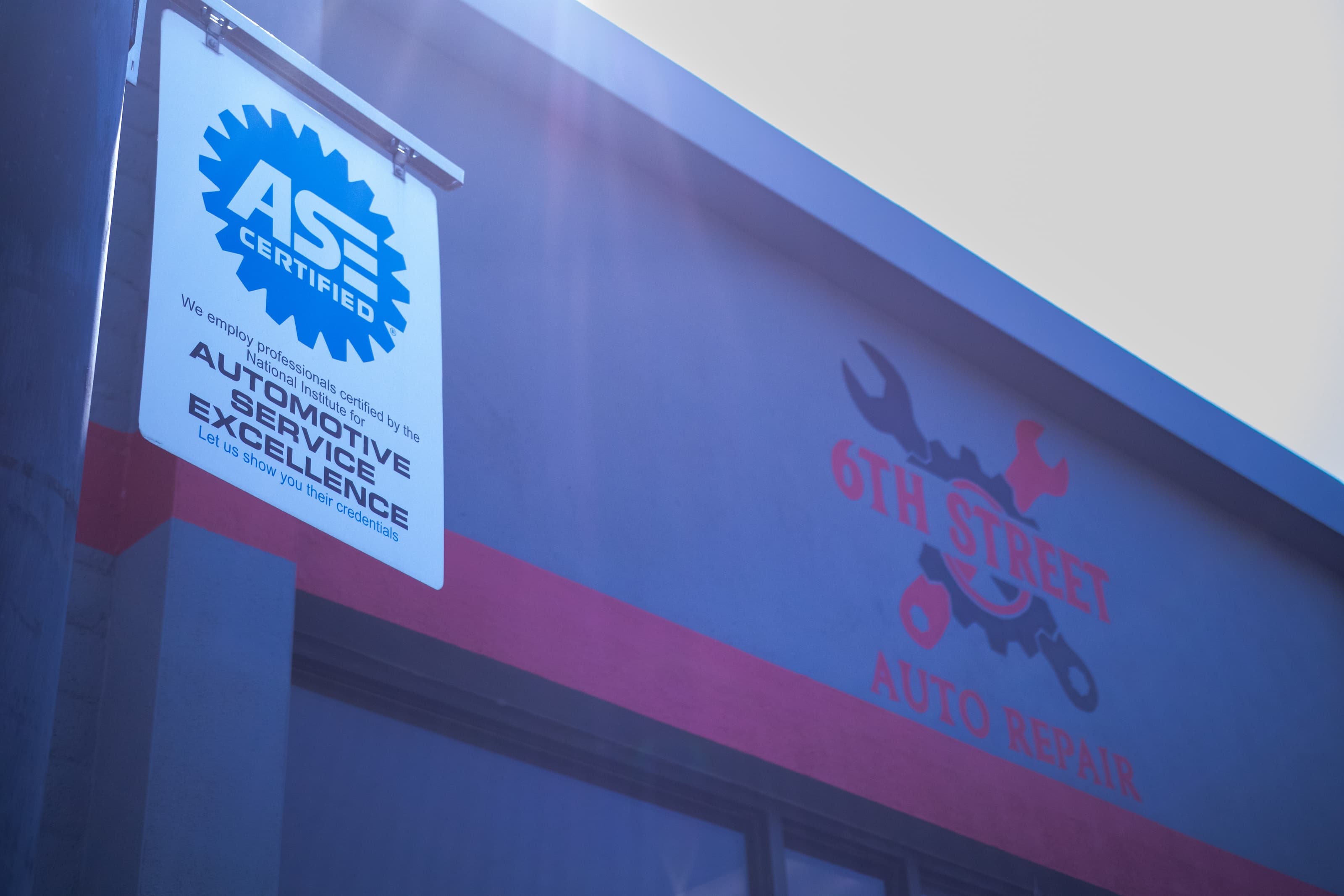 The ASE Certified sign and 6th Street Auto Repair logo on the shop's exterior